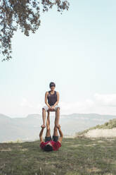 Man and woman practicing acroyoga in front of sky - PCLF00008