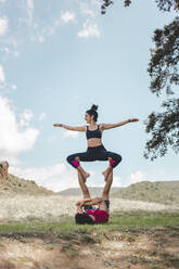 Junger Mann und Frau üben Acroyoga vor blauem Himmel - PCLF00011