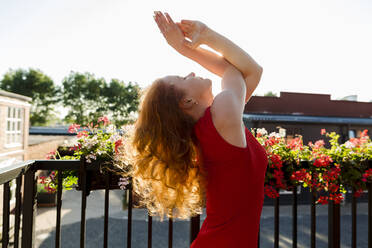 Woman wearing red dress with eyes closed practicing Garudasana - LLUF00867