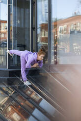 Woman doing stretching exercise on staircase - LLUF00874