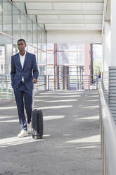 Young businessman walking with suitcase at railroad station - IFRF01711