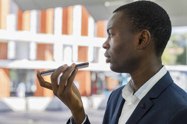 Young businessman talking on mobile phone at railroad station - IFRF01715