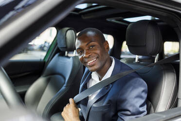 Happy businessman fastening seat belt in car - IFRF01733
