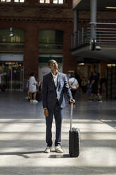Young businessman with luggage standing at railroad station - IFRF01752