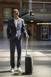 Businessman standing with luggage at railroad station - IFRF01753