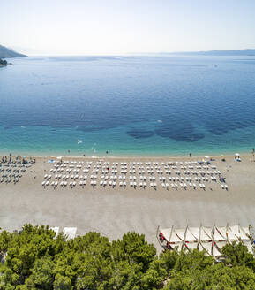 Luftaufnahme von aufgereihten Sonnenliegen am Strand von Zlatni Rat in Bol auf der Insel Brac, Kroatien. - AAEF15839