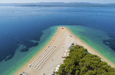 Luftaufnahme von aufgereihten Sonnenliegen am Strand von Zlatni Rat in Bol auf der Insel Brac, Kroatien. - AAEF15840