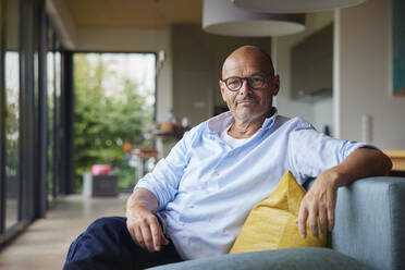 Retired senior man sitting on sofa at home - RBF08908