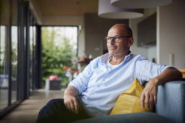 Nachdenklicher älterer Mann sitzt zu Hause auf dem Sofa - RBF08909