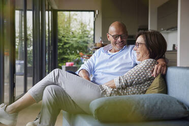 Glückliches älteres Paar sitzt zu Hause auf dem Sofa - RBF08948