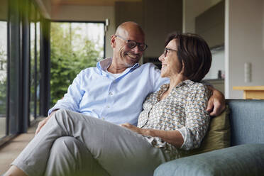 Loving senior couple sitting on sofa at home - RBF08950