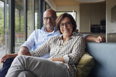 Cheerful senior woman with man sitting on sofa at home - RBF08959