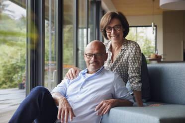 Happy man with woman sitting on sofa at home - RBF08961