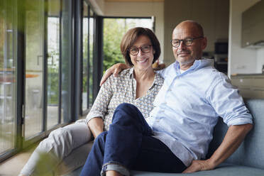 Happy senior man and woman sitting together on sofa at home - RBF08962