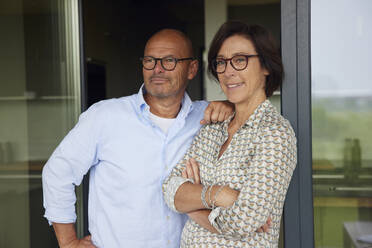 Lächelnder Mann mit Frau, die sich an eine Glastür lehnt - RBF08979