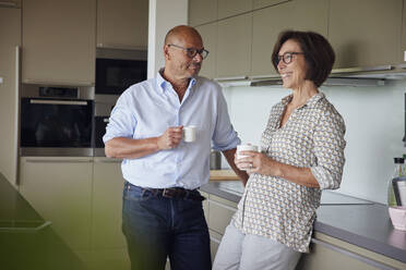 Happy woman with man standing in kitchen at home - RBF08991