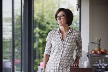 Thoughtful senior woman standing by kitchen island at home - RBF09018