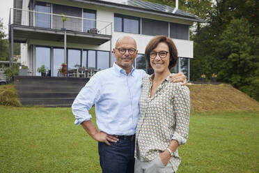 Happy senior woman with man standing in front of house - RBF09025