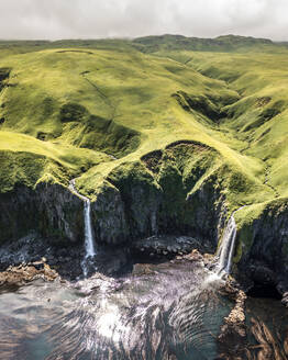 Luftaufnahme eines Wasserfalls an der Küste, Driftwood Bay, Insel Unalaska, Alaska, Vereinigte Staaten. - AAEF15935