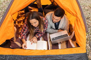 Von oben Paar Camping in bunten Zelt, Kaffee trinken, lesen Buch und Surfen auf dem Laptop - ADSF38907