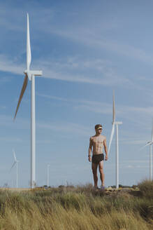 Junger Sportler ohne Hemd vor einer Windkraftanlage - MTBF01256