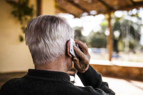 Älterer Mann telefoniert auf der Veranda seines Hauses - ADSF38915