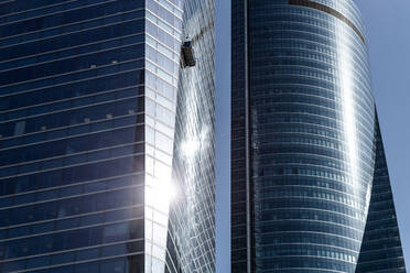 Von unten des modernen mehrstöckigen Gebäudes mit Glasfenstern auf dem Hintergrund des blauen Himmels an einem sonnigen Tag im Stadtzentrum - ADSF38925