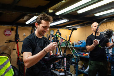 Mechaniker beim Einstellen von Schrauben an modernen Fahrradschuhen in der Werkstatt - ADSF38928