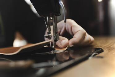 Man stitching textile in atelier - ADSF38931