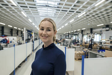 Lächelnde Geschäftsfrau mit blondem Haar in einer Fabrik - JOSEF13280