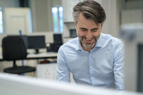 Glücklicher reifer Geschäftsmann am Schreibtisch im Büro - JOSEF13293