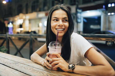 Glückliche schöne Frau mit Smoothie-Getränk in einem Straßencafé - OYF00803