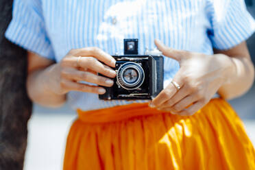 Woman holding vintage analog camera on sunny day - JOSEF13315