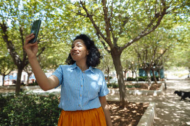 Woman taking selfie through smart phone at park - JOSEF13347