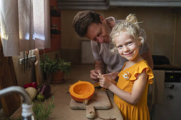 Lächelndes Mädchen mit Vater bei der Essenszubereitung in der Küche - SVKF00569