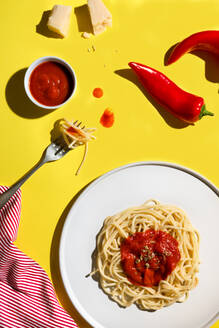 Von oben appetitlich frisch gekochte Spaghetti mit roter Soße und Gewürzdip rote Paprika Käse und Gabel auf gelbem Hintergrund - ADSF39014