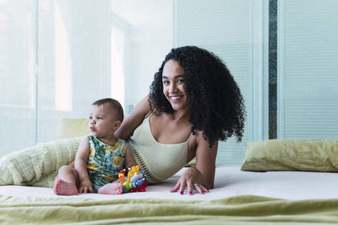 Happy woman with baby boy on bed at home - PNAF04544