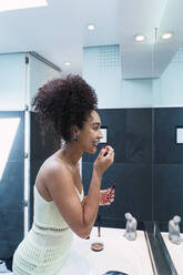 Woman applying lipstick in bathroom at home - PNAF04558