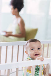 Happy cute baby boy in crib at home - PNAF04587