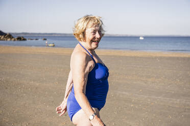 Glückliche ältere Frau genießt am Strand an einem sonnigen Tag - UUF27314