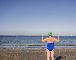 Senior woman in swimsuit looking at sea on sunny day - UUF27327