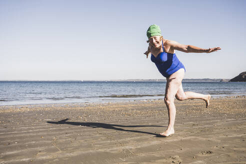 Frau hat Spaß beim Laufen am Strand an einem sonnigen Tag - UUF27331