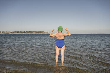 Woman flexing muscles amidst sea - UUF27337