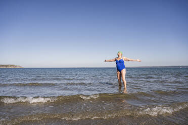 Woman with arms outstretched amidst sea enjoying sunshine - UUF27339