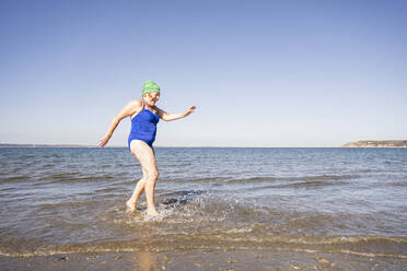 Frau hat Spaß beim Spielen im Meer an einem sonnigen Tag - UUF27341