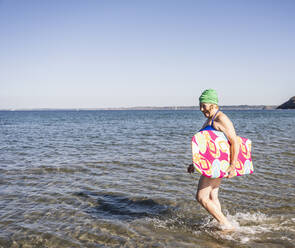 Glückliche Frau mit Surfbrett genießt im Meer - UUF27350