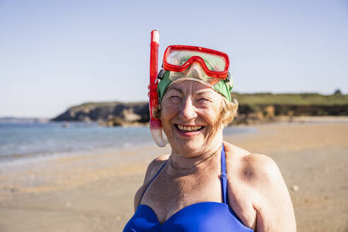 Glückliche Frau mit Taucherbrille und Schnorchelmaske am Strand - UUF27355