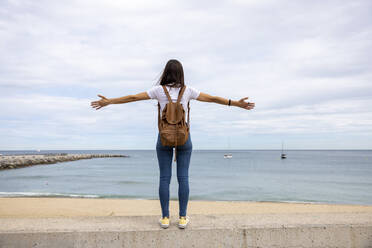 Woman with arms outstretched on wall - WPEF06513