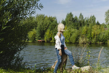 Senior woman looking at lake on sunny day - SEAF01277