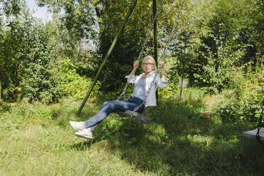 Senior woman enjoying swing in garden - SEAF01291